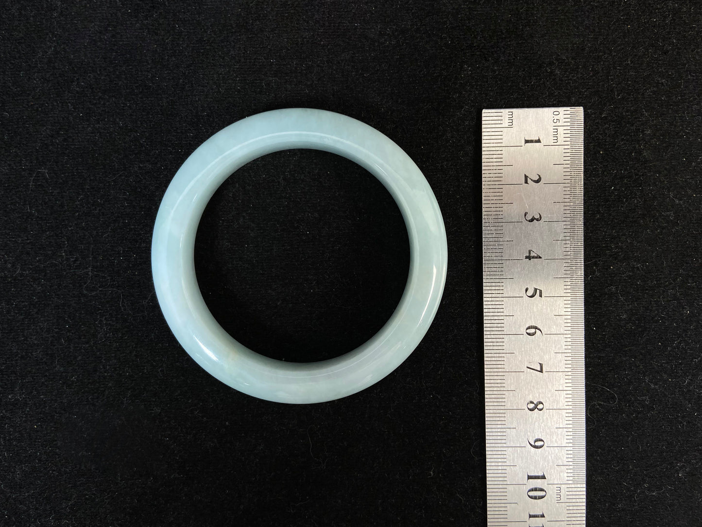 This bracelet showcases a pale green jade with a subtle purple hue.