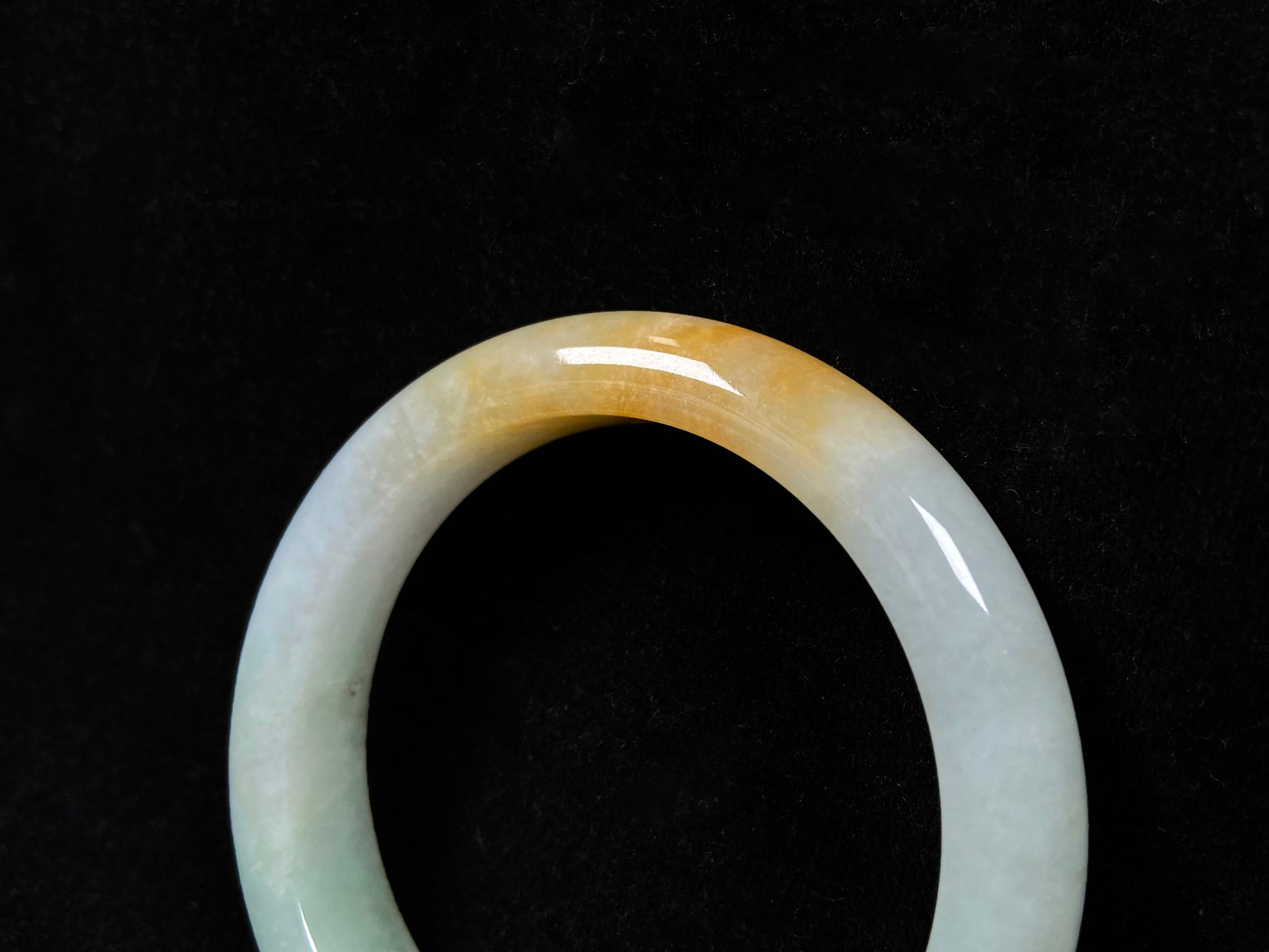 A light green jadeite bangle with a bold splash of gold.