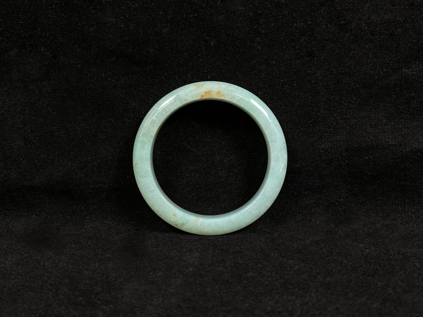 A light green jadeite bangle with gold speckles.