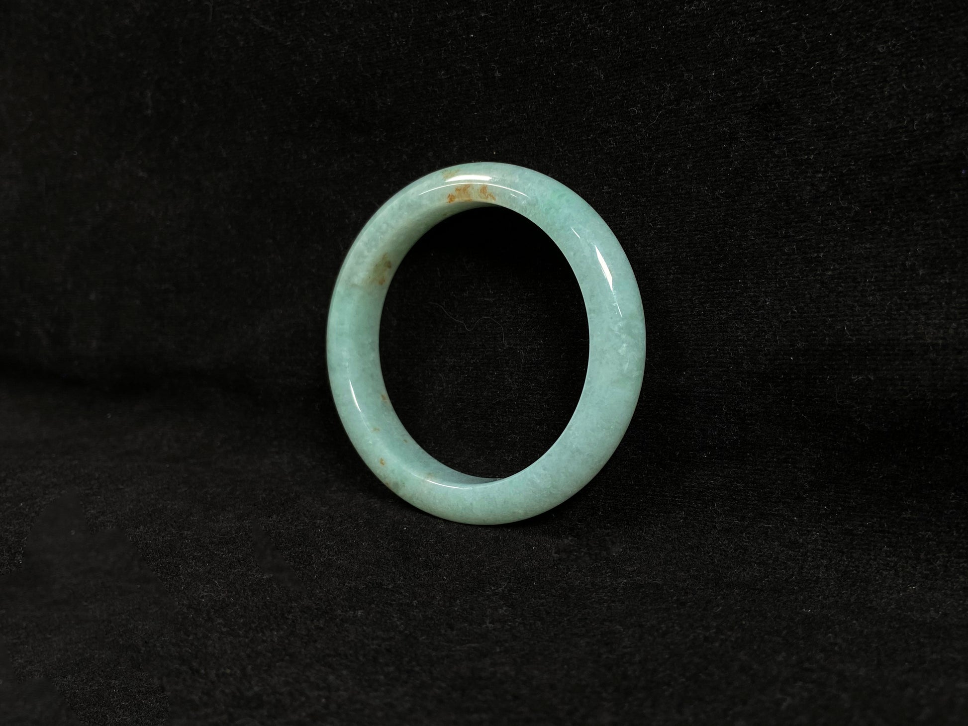 A light green jadeite bangle with gold speckles.
