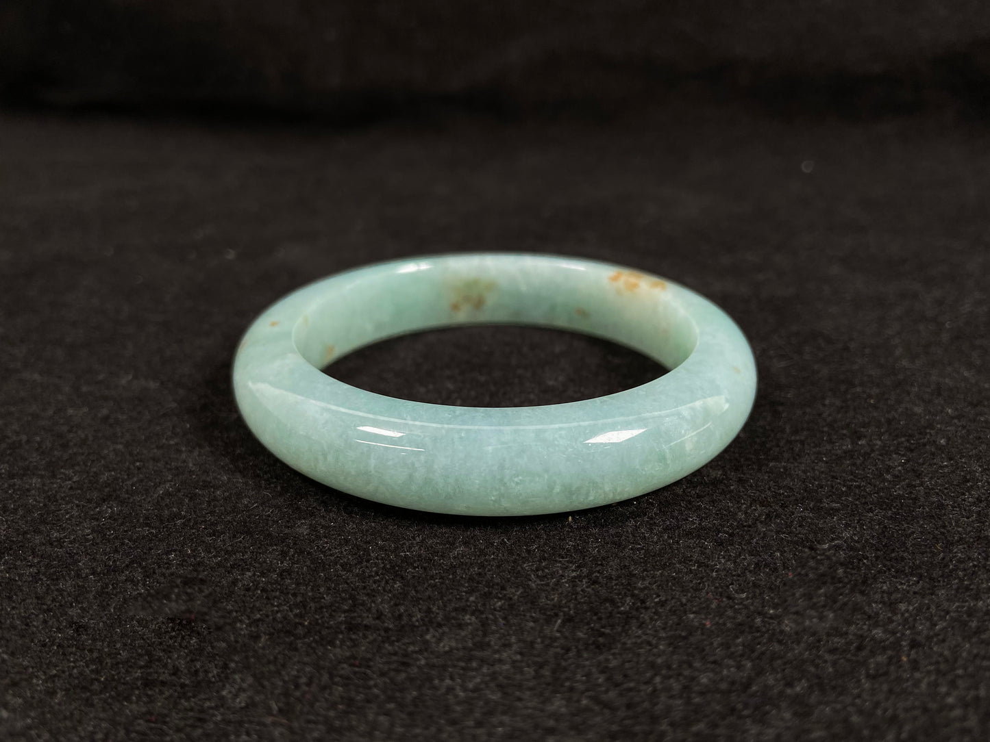 A light green jadeite bangle with gold speckles.