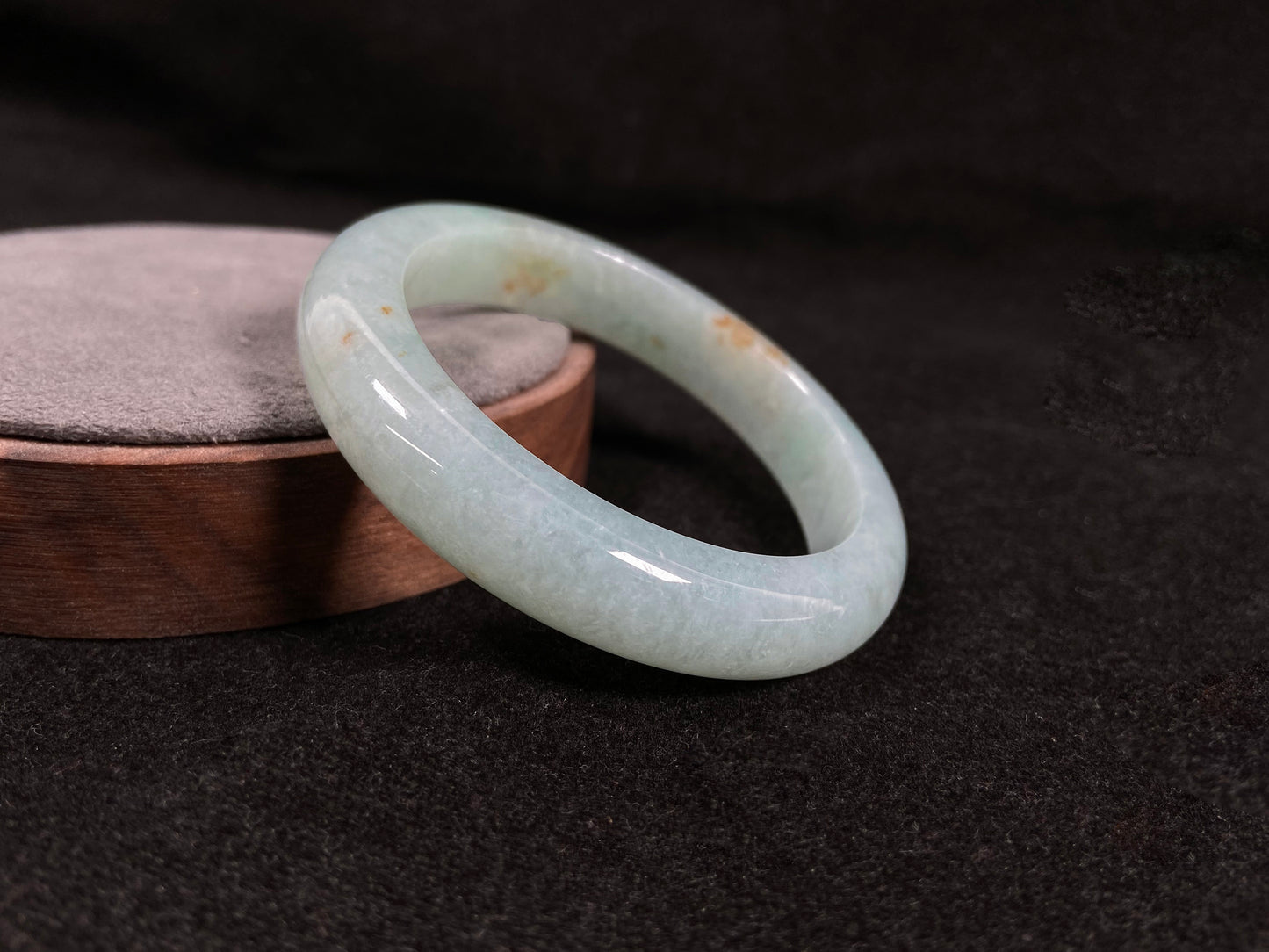 A light green jadeite bangle with gold speckles.