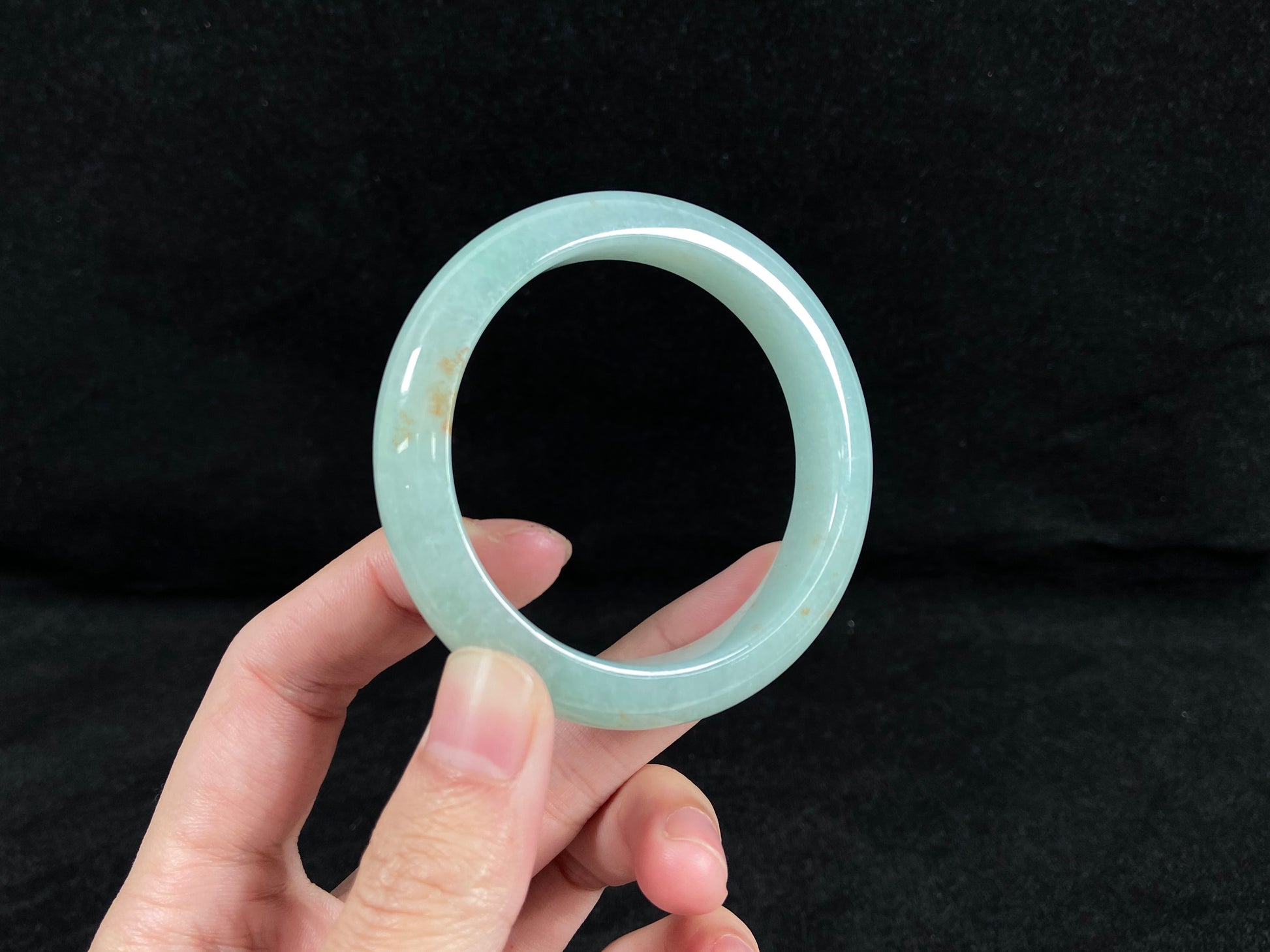 A light green jadeite bangle with gold speckles.