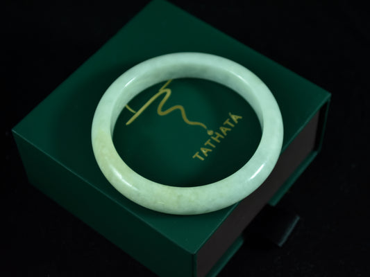 Green jade bracelet on a green box with 'TATHATA' branding.