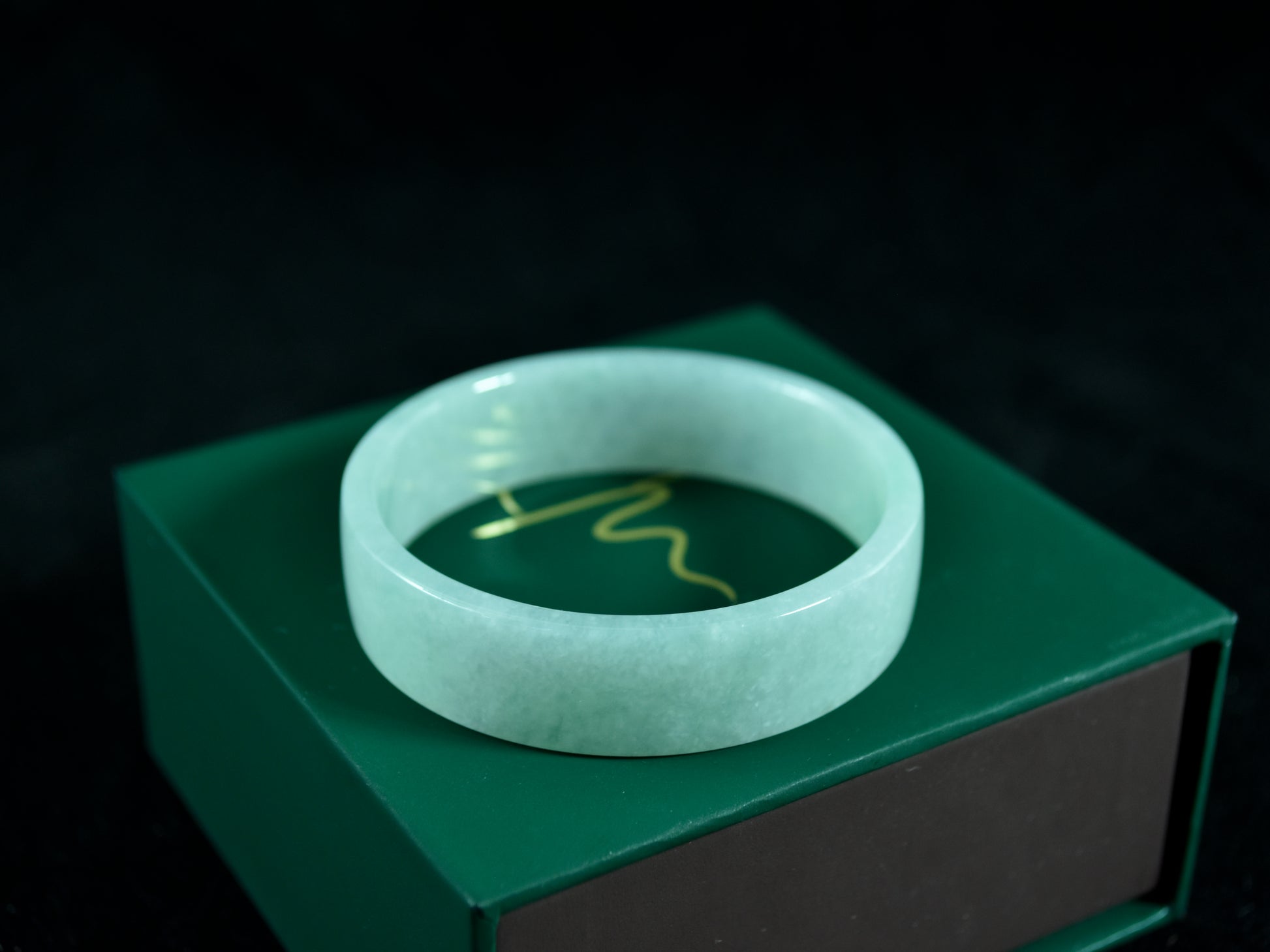 Green jade bracelet on a green box with a dark background