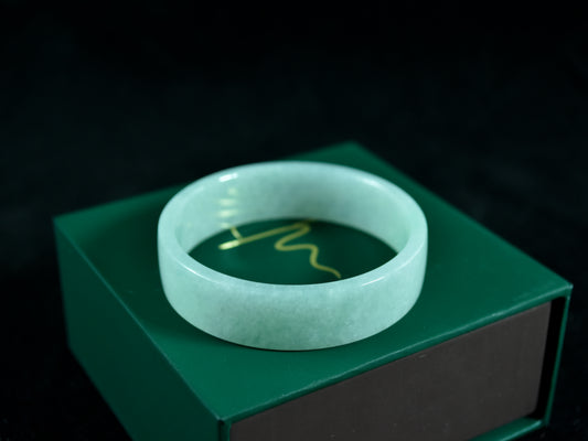 Green jade bracelet on a green box with a dark background