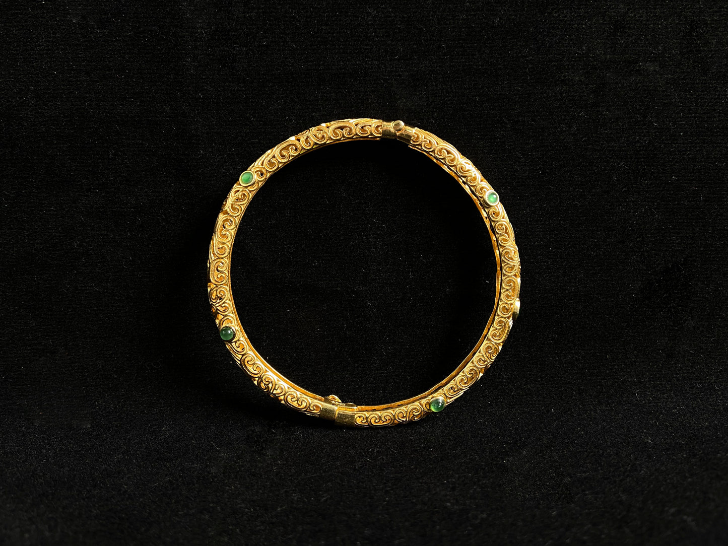 A gold plated openwork bangle with cloud motifs, set with nine light green jade beads.
