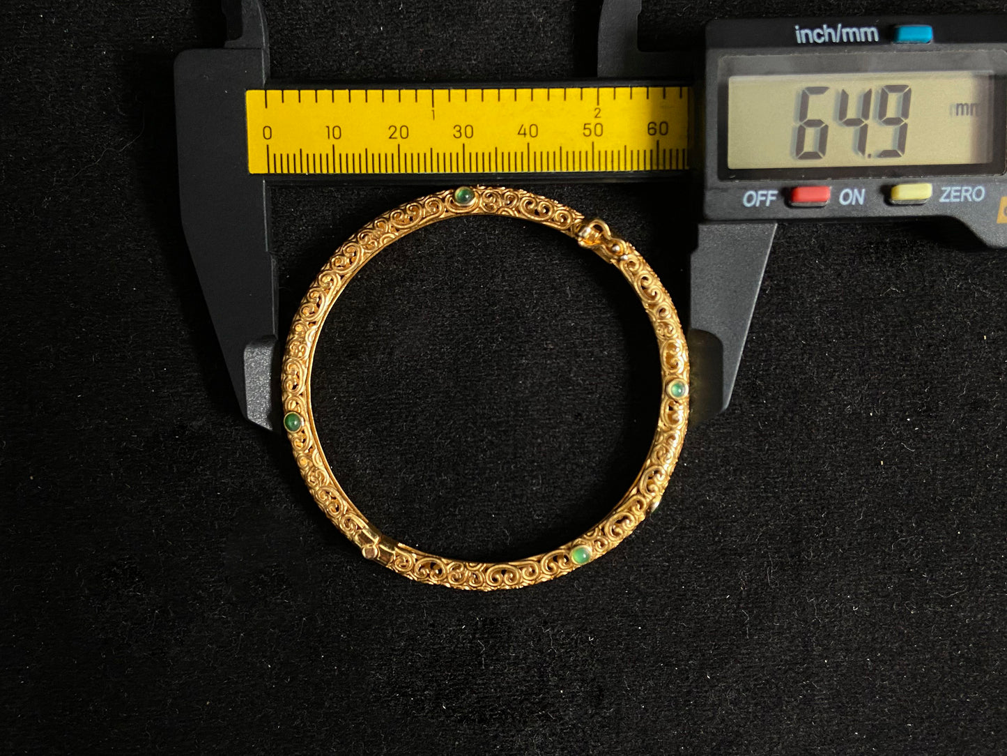 A gold plated openwork bangle with cloud motifs, set with nine light green jade beads.