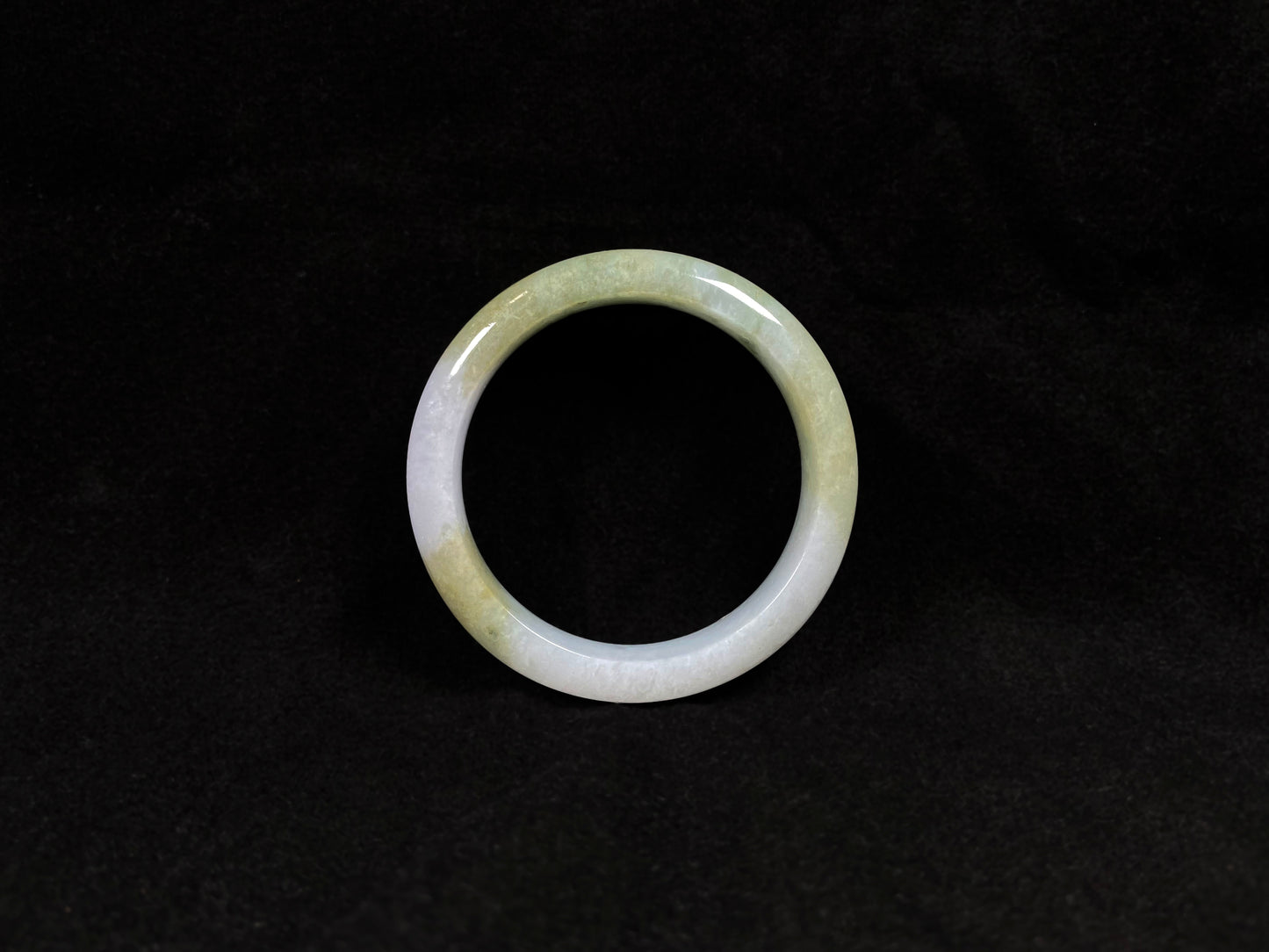 A creamy white jadeite bangle adorned with splashes of yellow-green.