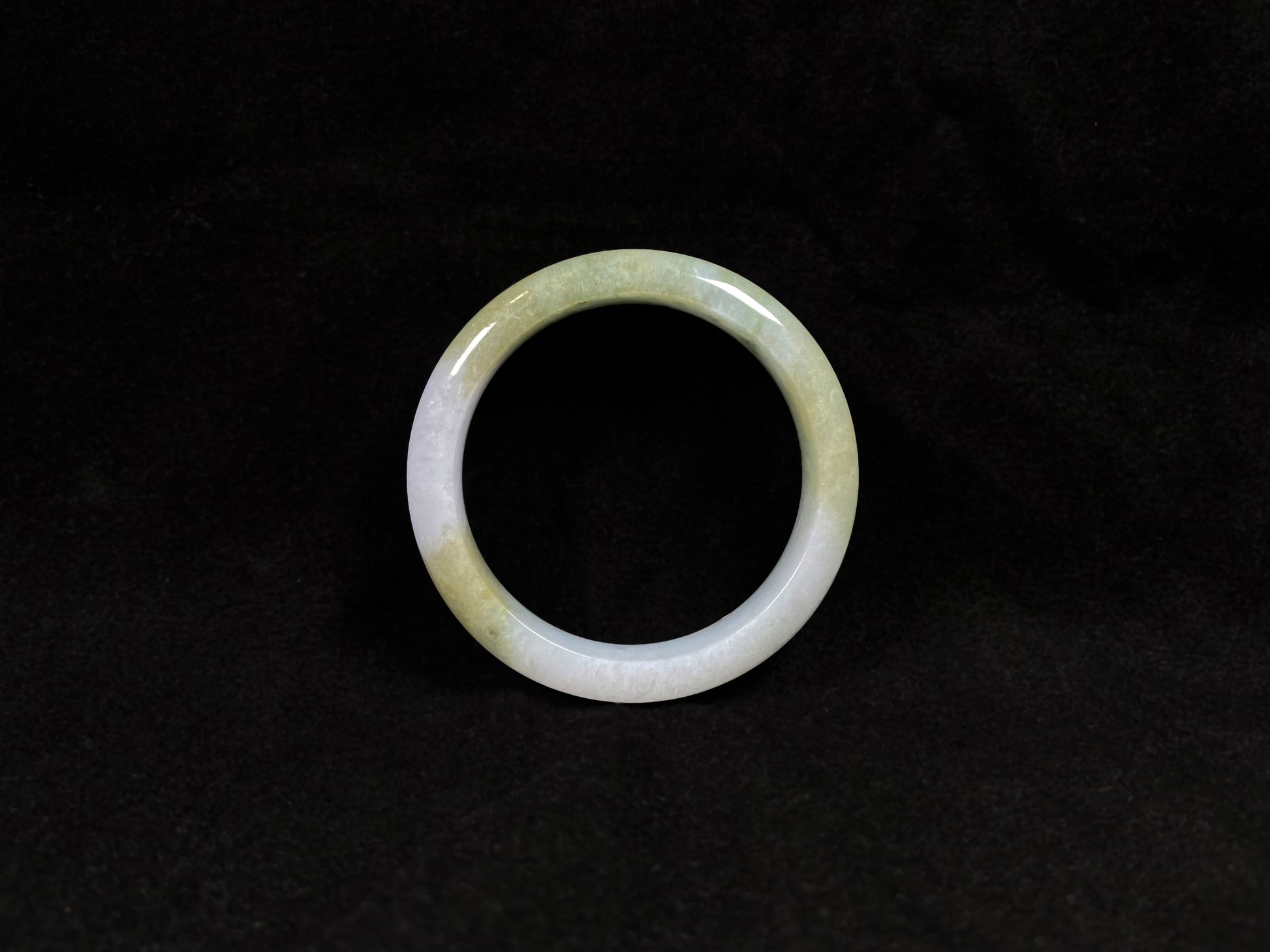 A creamy white jadeite bangle adorned with splashes of yellow-green.
