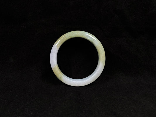 A creamy white jadeite bangle adorned with splashes of yellow-green.