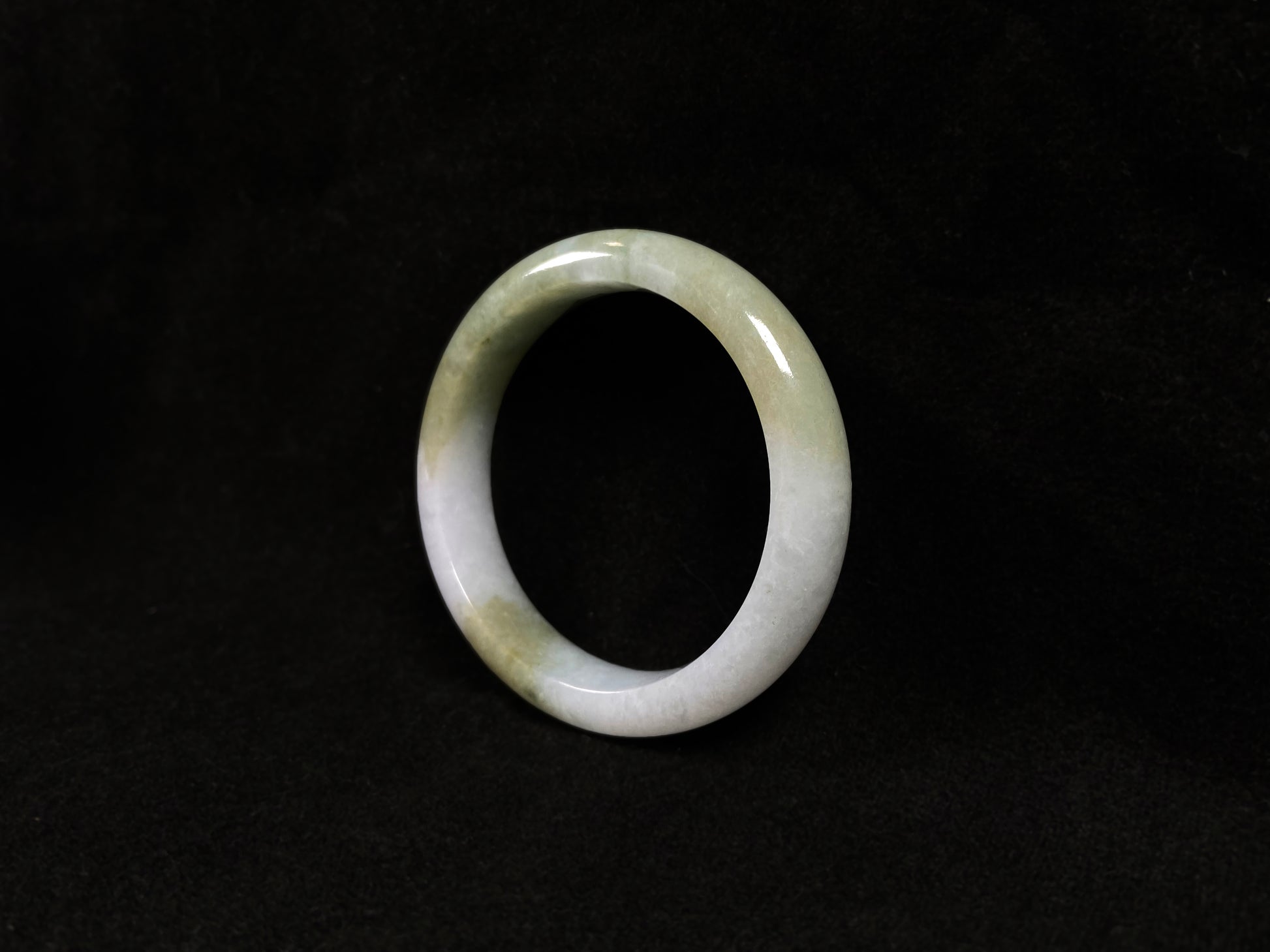 A creamy white jadeite bangle adorned with splashes of yellow-green.