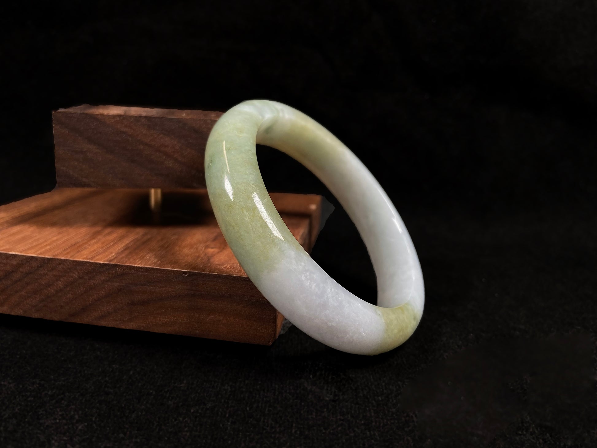 A creamy white jadeite bangle adorned with splashes of yellow-green.