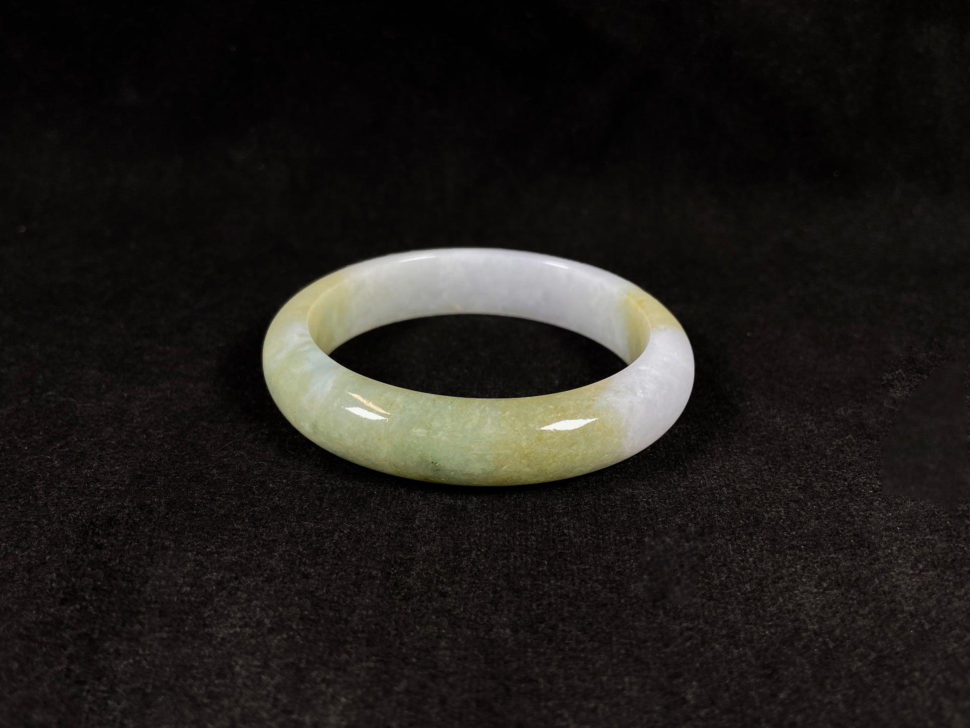 A creamy white jadeite bangle adorned with splashes of yellow-green.