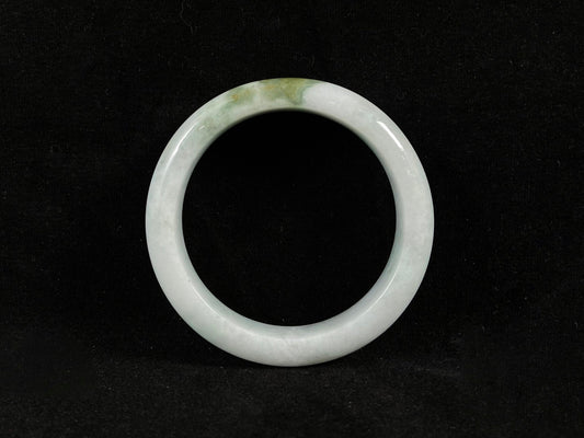 A pearl-white jade bangle embraced by a soft green mountain-water gradient.
