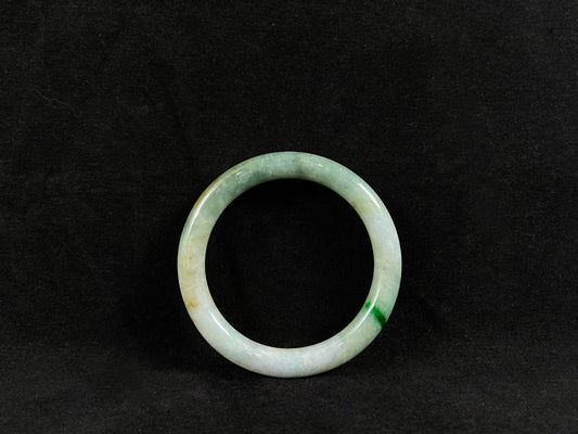 A jade bangle traced with a single emerald vein.
