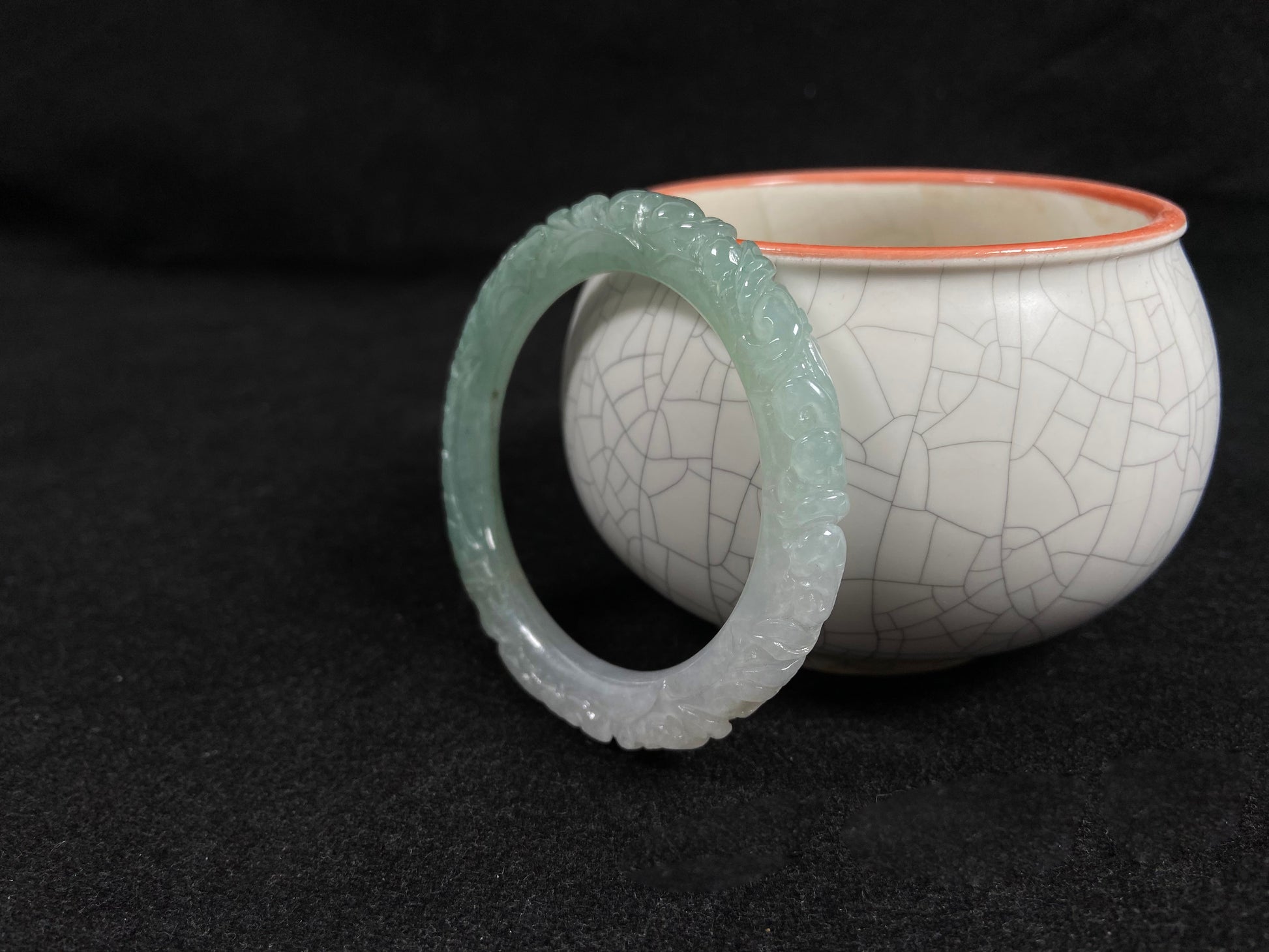 A carved jadeite bangle with half green and half white sections.
