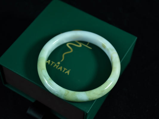 Green jade bracelet on a green box with 'ATHATA' branding.