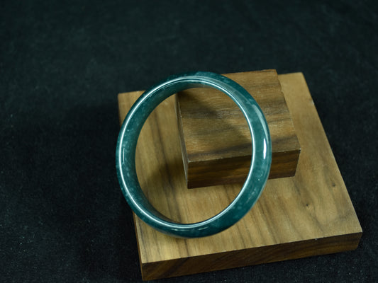Green jade ring on a wooden stand against a dark background