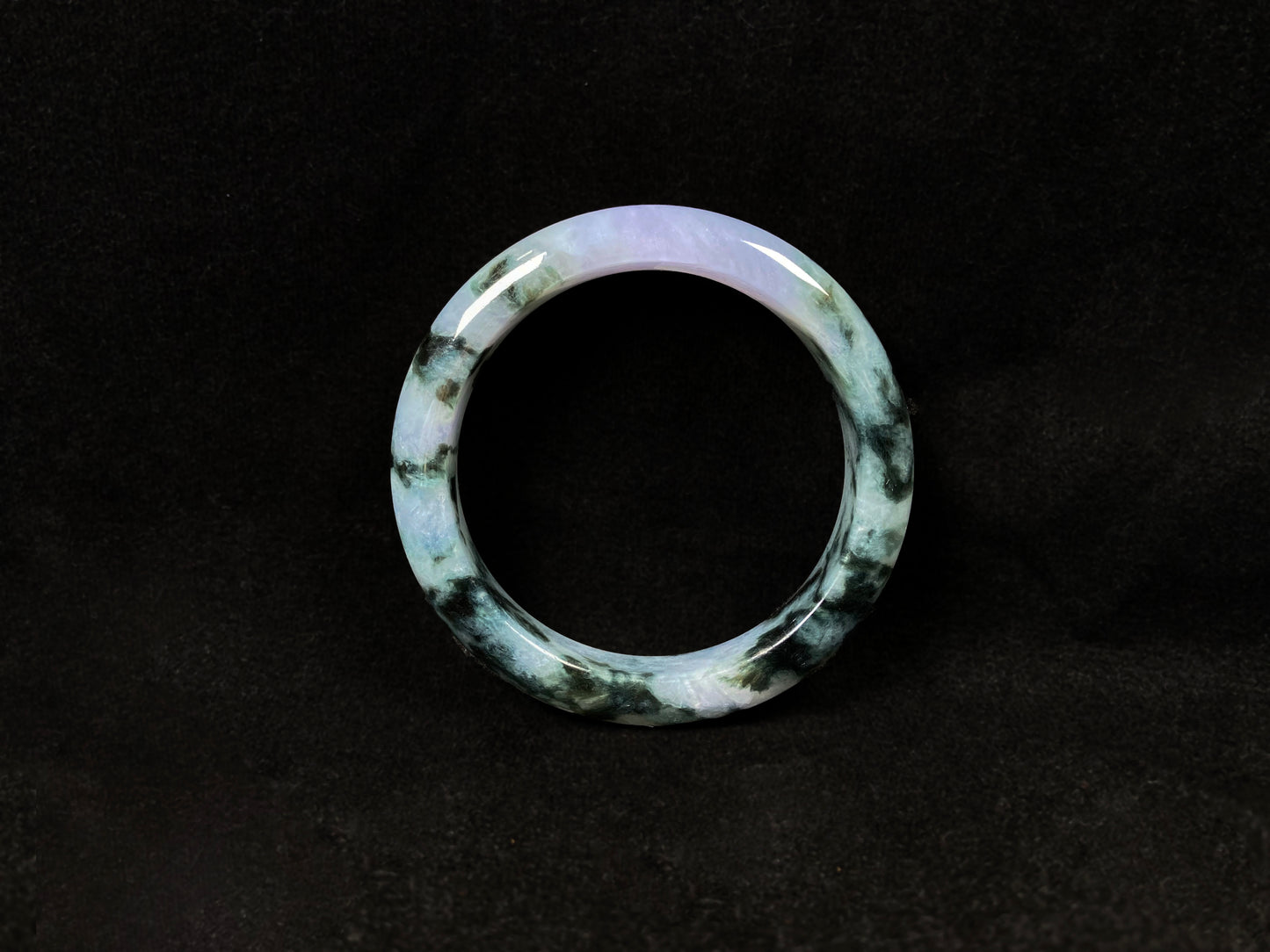 A jadeite bangle with purple and floating ink-green hues.