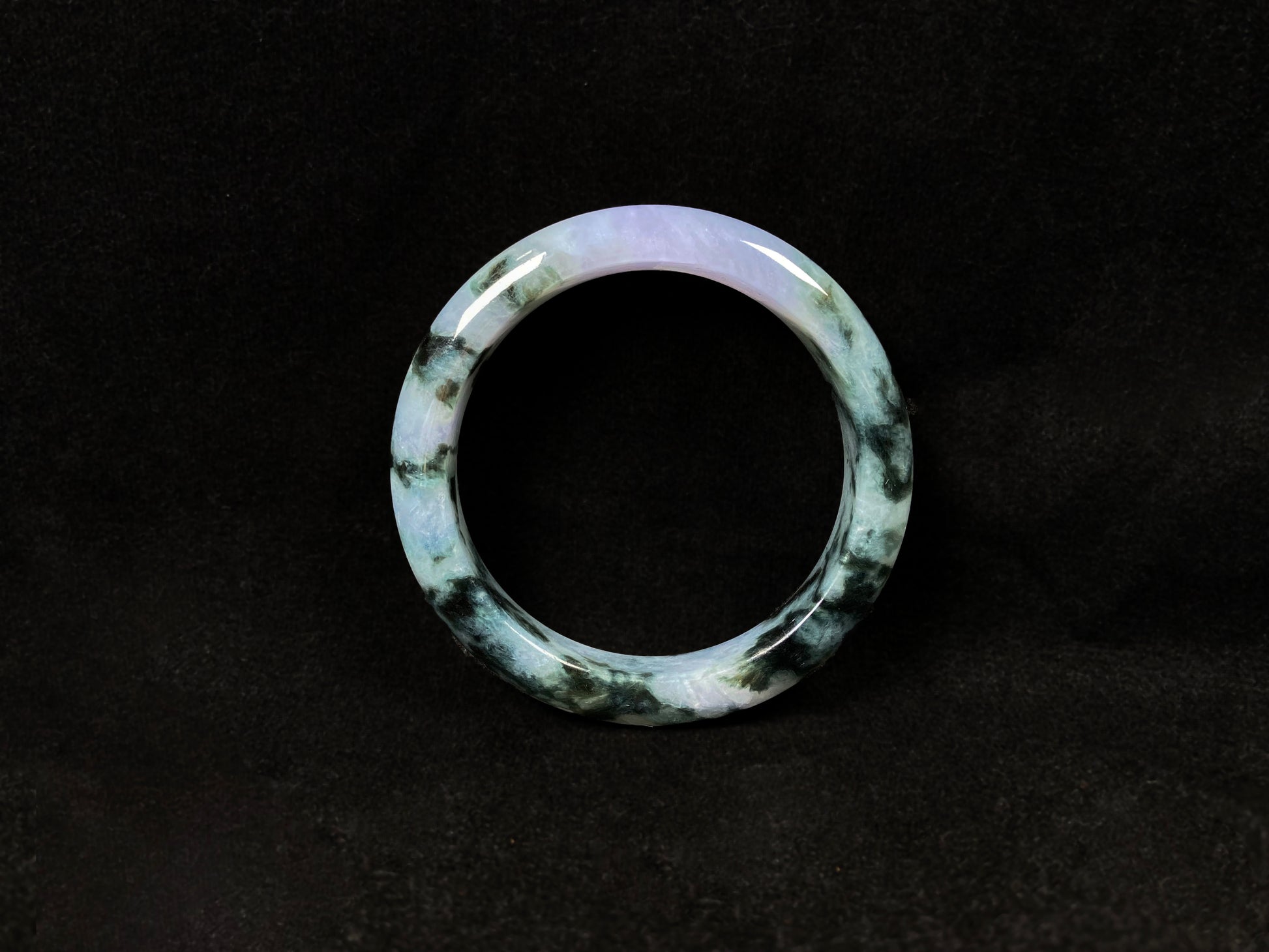 A jadeite bangle with purple and floating ink-green hues.