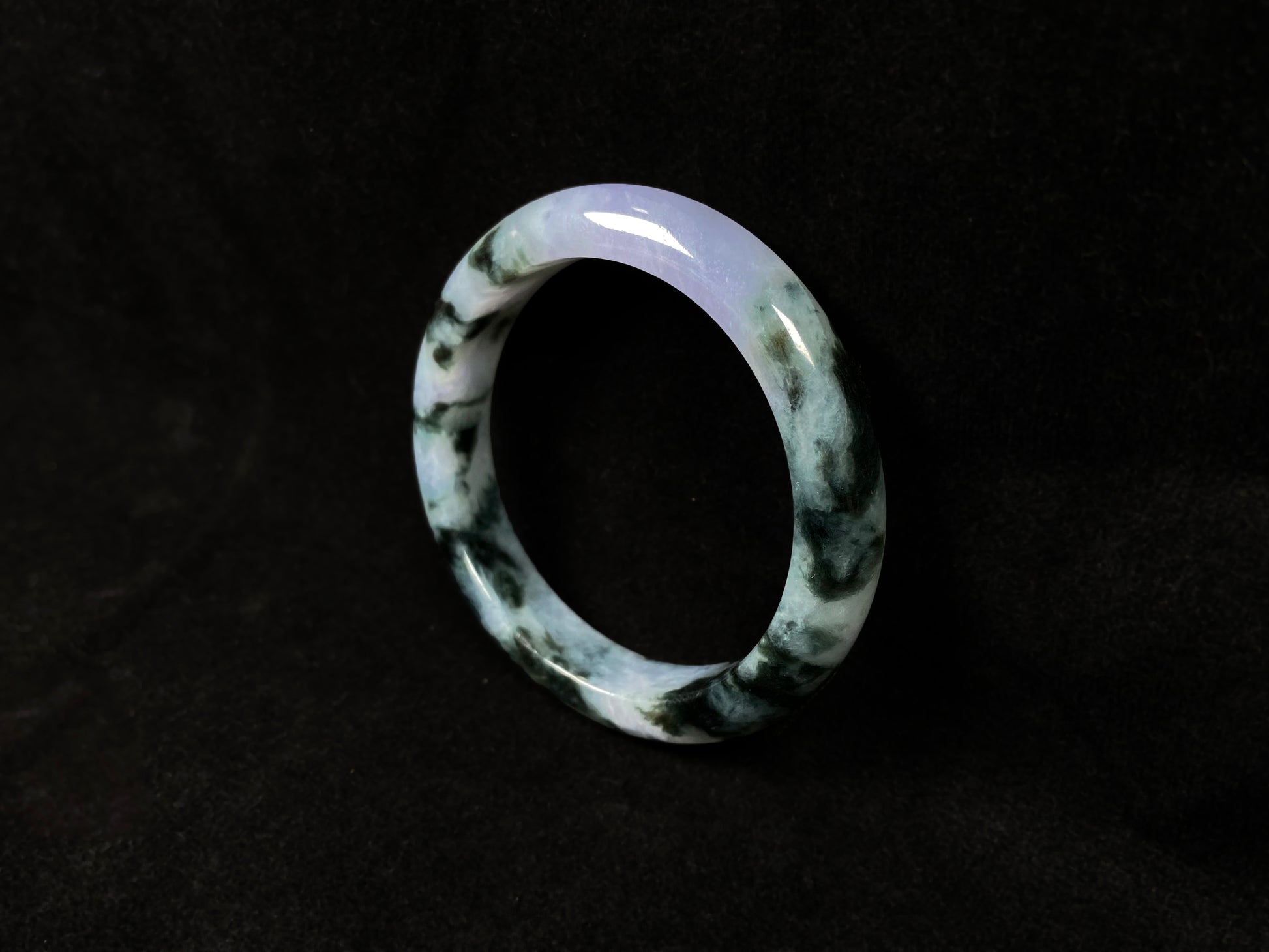 A jadeite bangle with purple and floating ink-green hues.