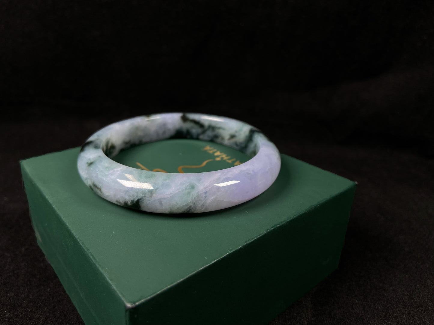 A jadeite bangle with purple and floating ink-green hues.