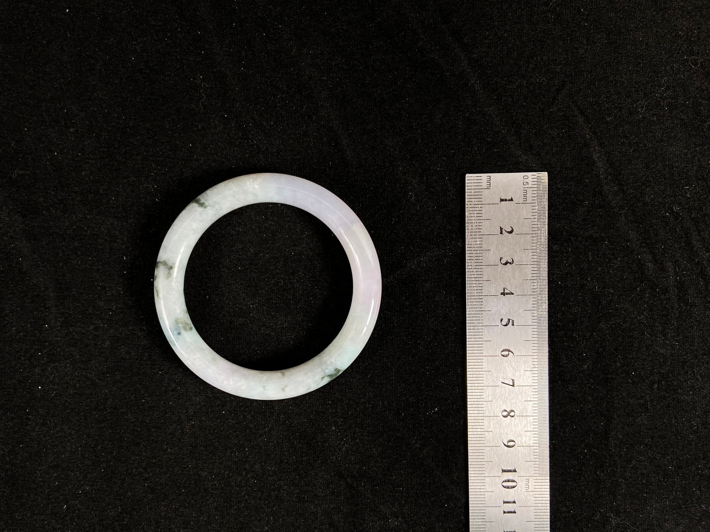 
Nestled against the measuring tape, the bangle reveals its striking marbled pattern of deep forest green and creamy ivory.