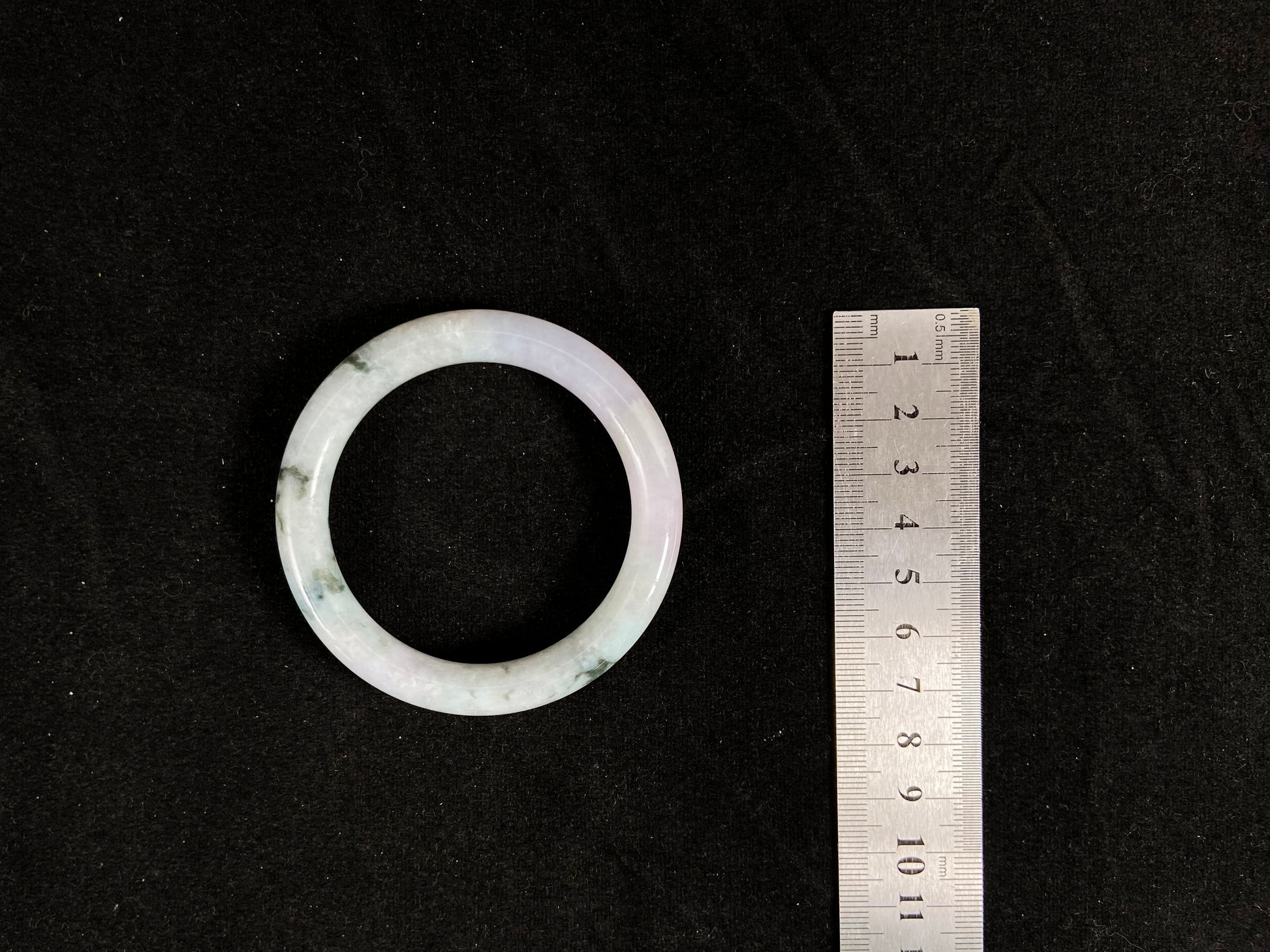 
Nestled against the measuring tape, the bangle reveals its striking marbled pattern of deep forest green and creamy ivory.