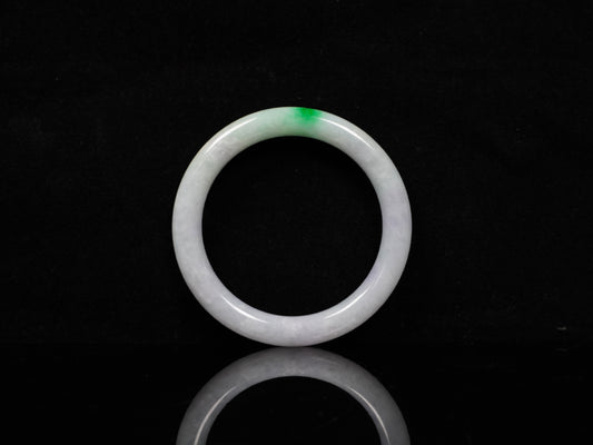 A milky white with delicate green accents jadeite bangle.