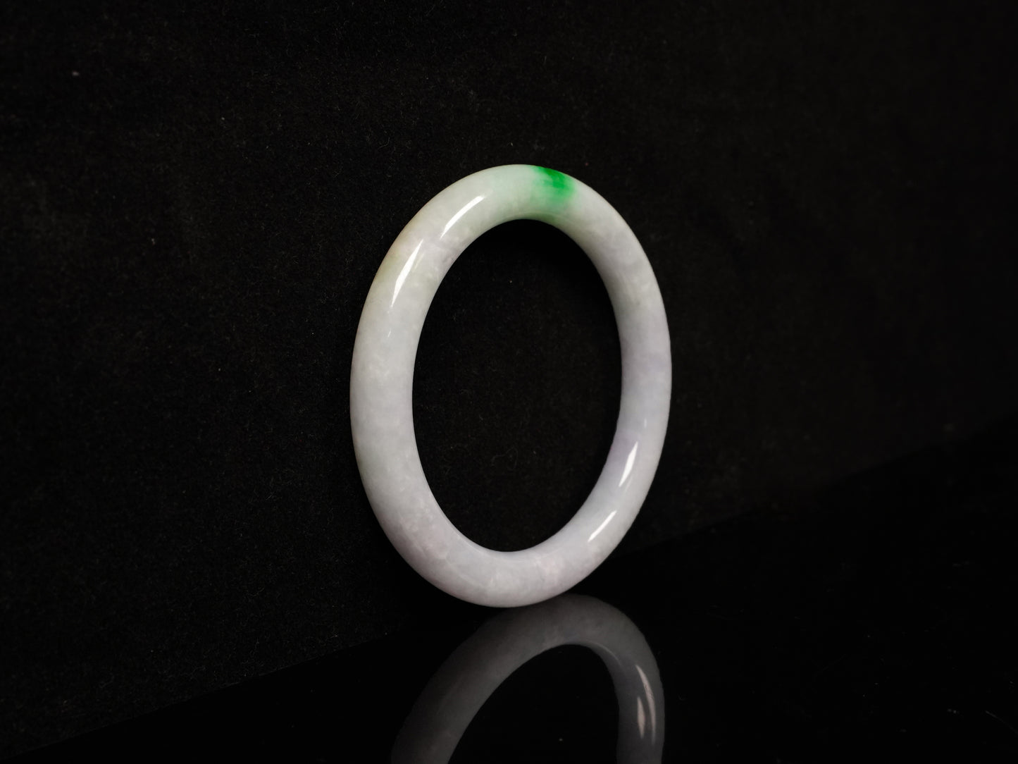 A milky white with delicate green accents jadeite bangle.