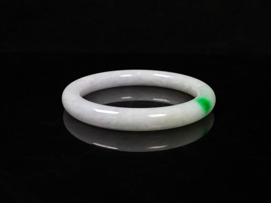 A milky white with delicate green accents jadeite bangle.