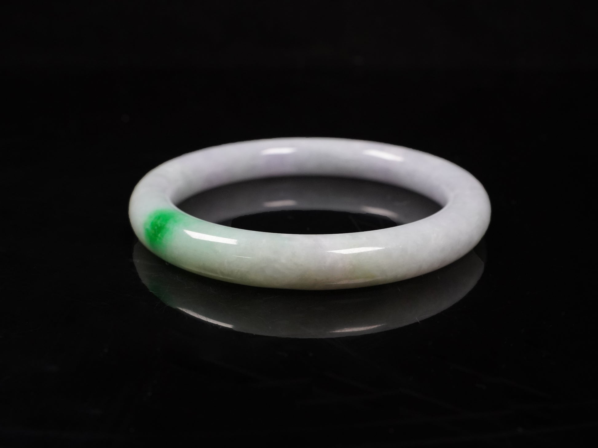 A milky white with delicate green accents jadeite bangle.
