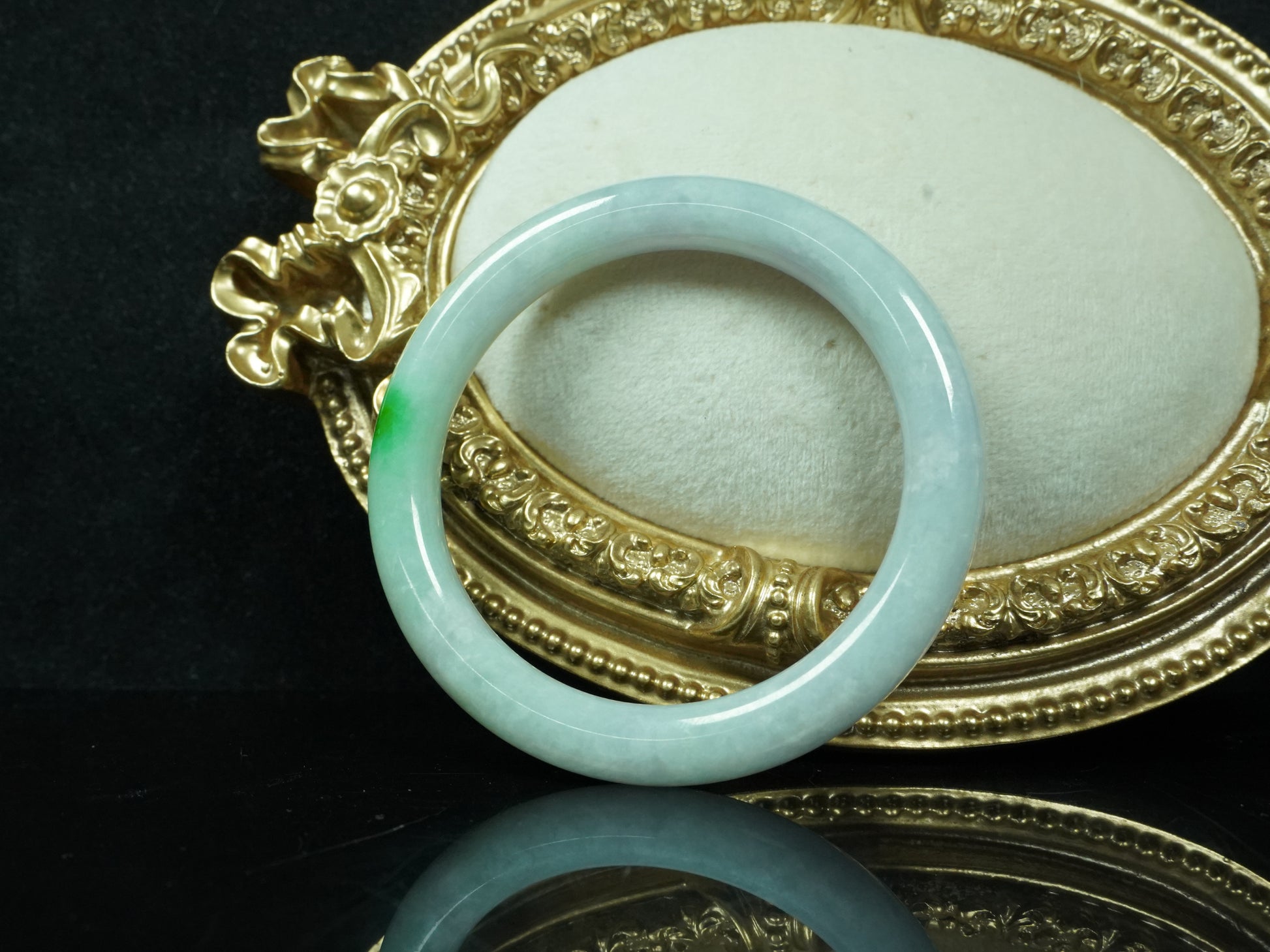 A milky white with delicate green accents jadeite bangle.