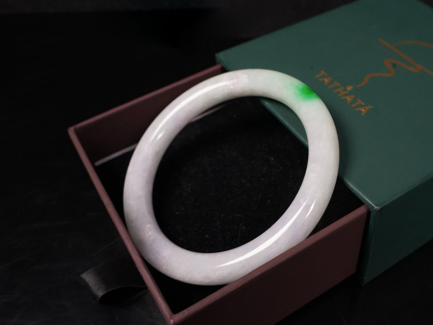 A milky white with delicate green accents jadeite bangle.