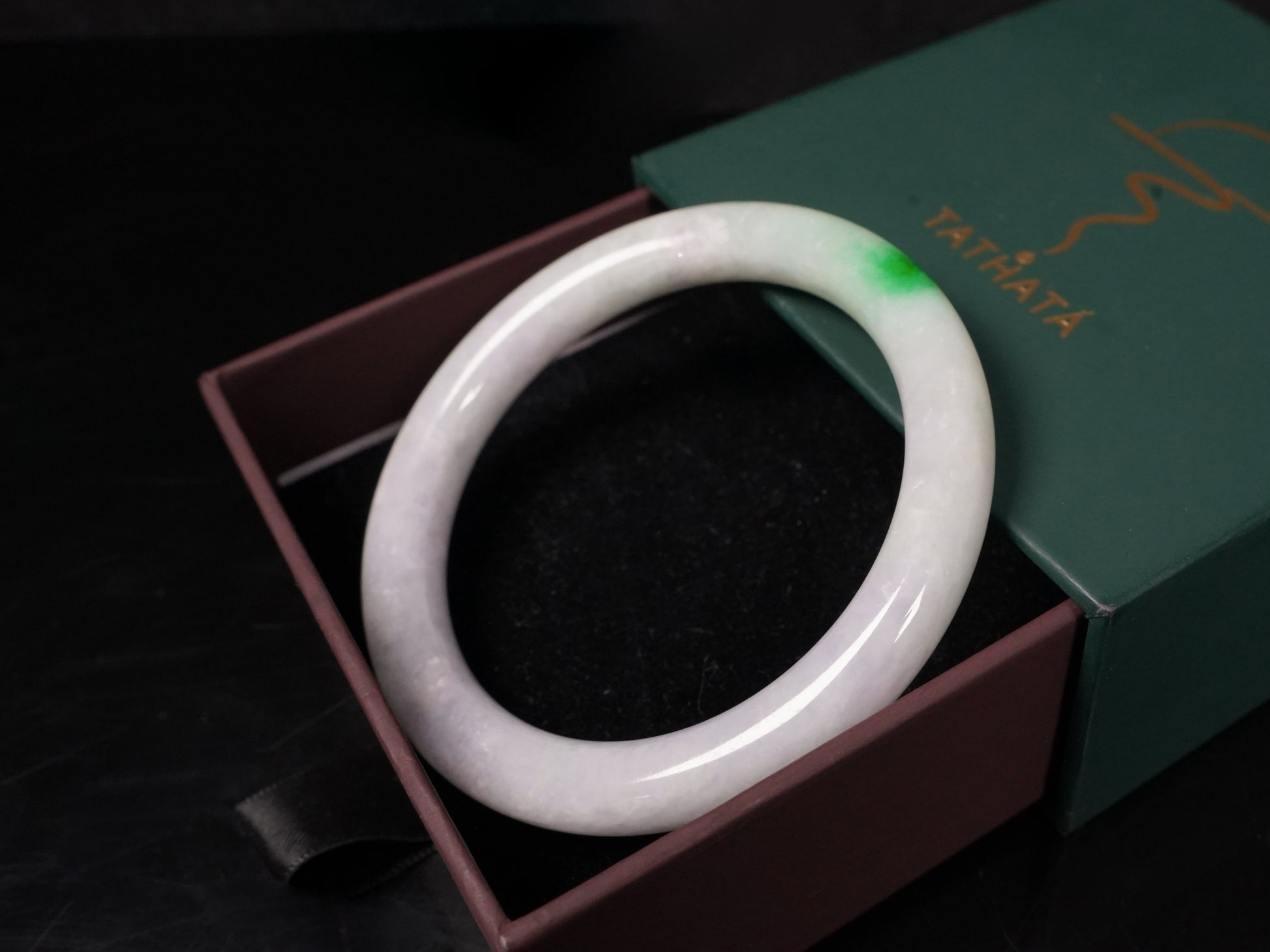 A milky white with delicate green accents jadeite bangle.