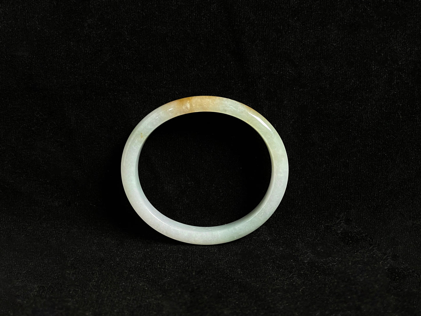 This jade bangle features a creamy white base adorned with delicate gold sprinkles, creating an elegant two tone effect.