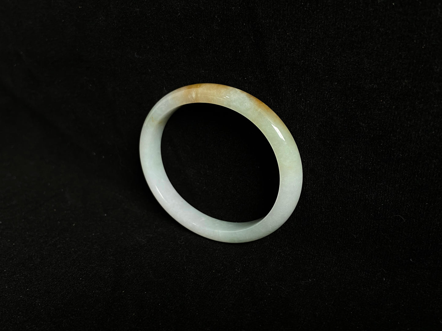 This jade bangle features a creamy white base adorned with delicate gold sprinkles, creating an elegant two tone effect.