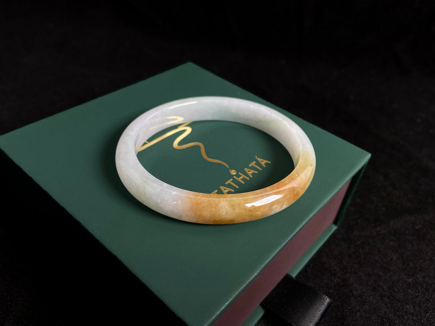 This jade bangle features a creamy white base adorned with delicate gold sprinkles, creating an elegant two tone effect.