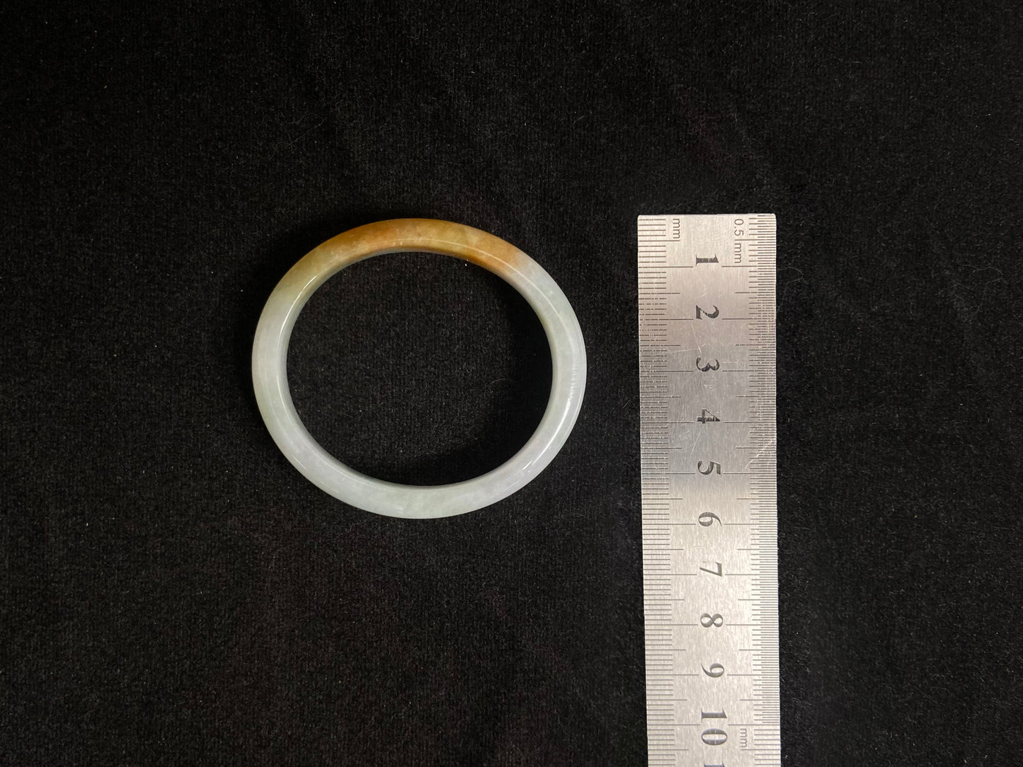 This jade bangle features a creamy white base adorned with delicate gold sprinkles, creating an elegant two tone effect.