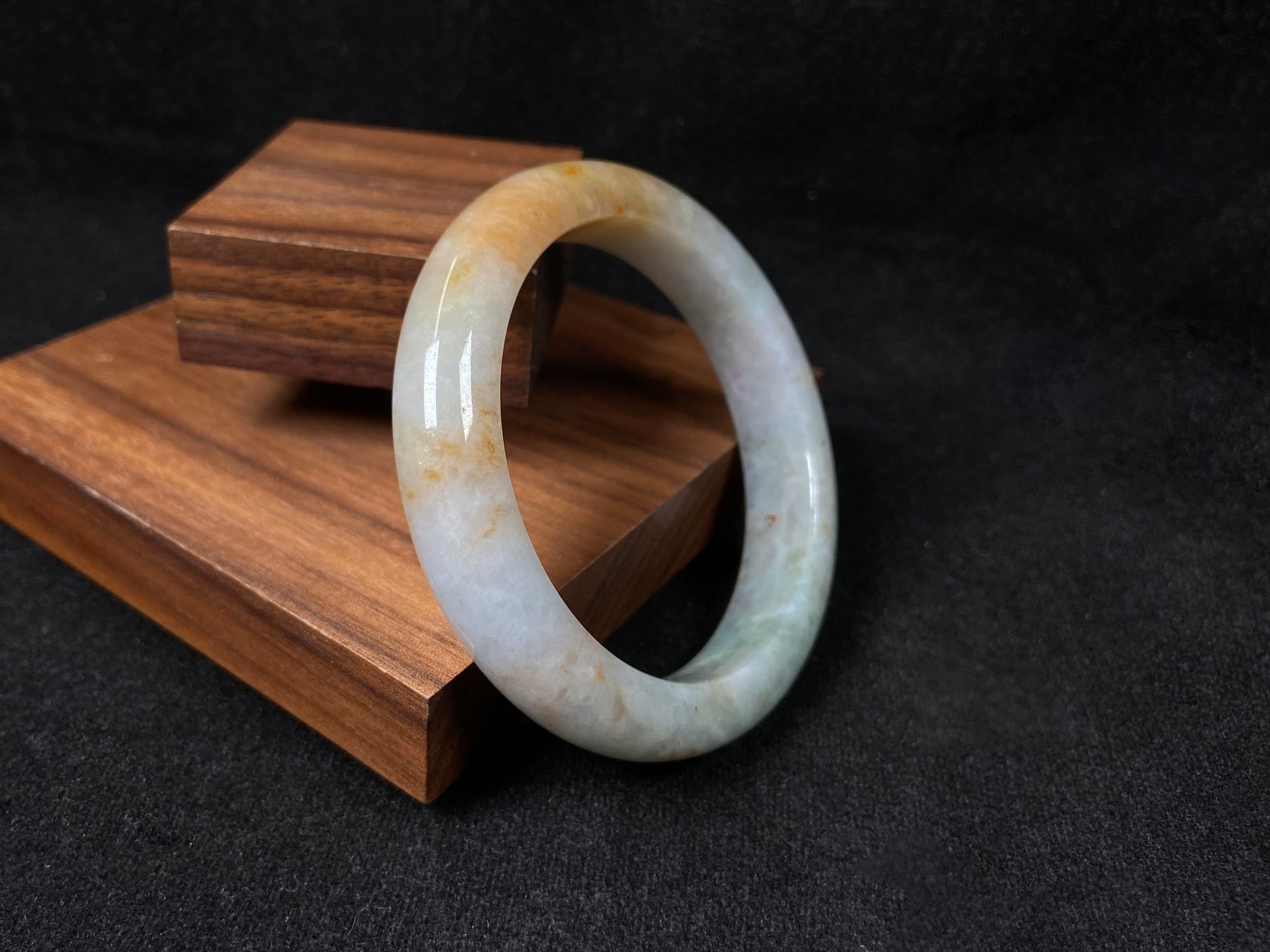 A creamy white jadeite bangle with subtle green undertones and gold sprinkles.