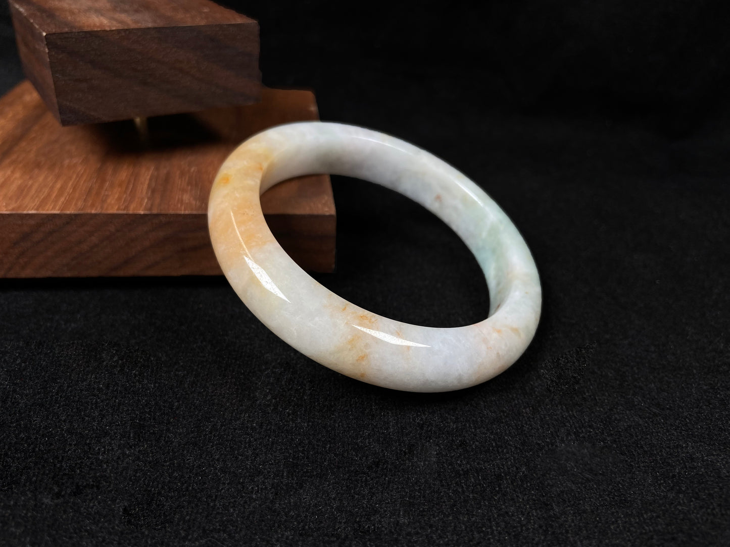 A creamy white jadeite bangle with subtle green undertones and gold sprinkles.