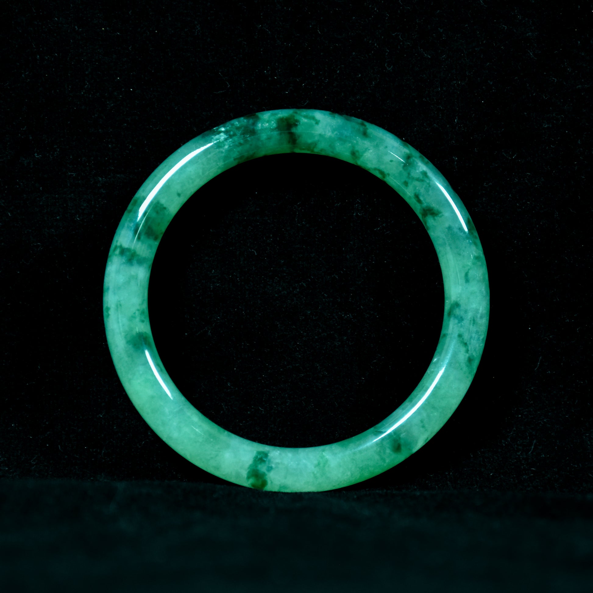 Green jade ring on a black background