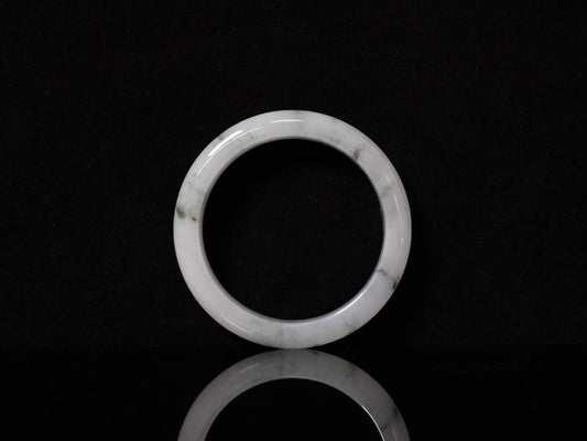 This jadeite bangle features a milky base adorned with delicate ink-wash veining.