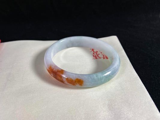 Jade bracelet with red markings on a white surface