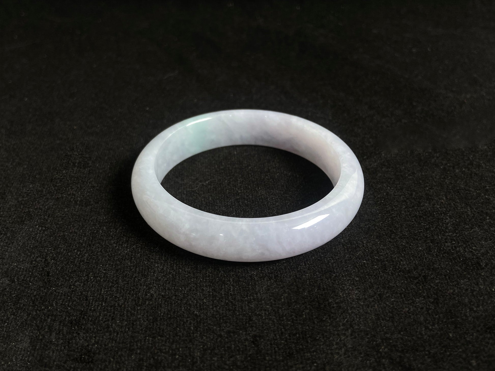 This jade bangle features a creamy white oval shaped Guifei design, known for its elegant and comfortable fit.
