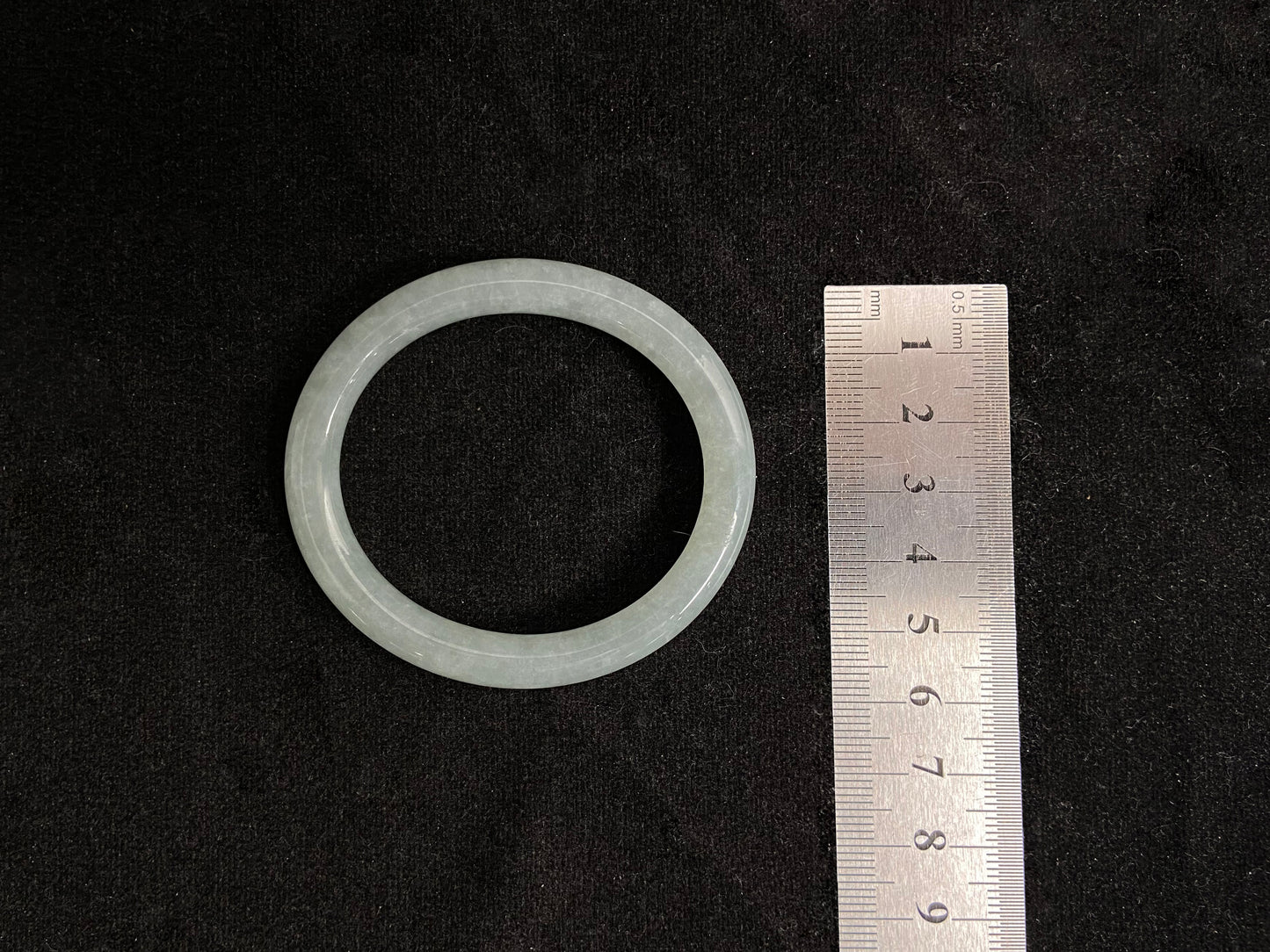 This delicate jade bangle features a pale green hue and slender circular profile, with finely crafted thin rods that create an elegant, youthful feminine aesthetic.