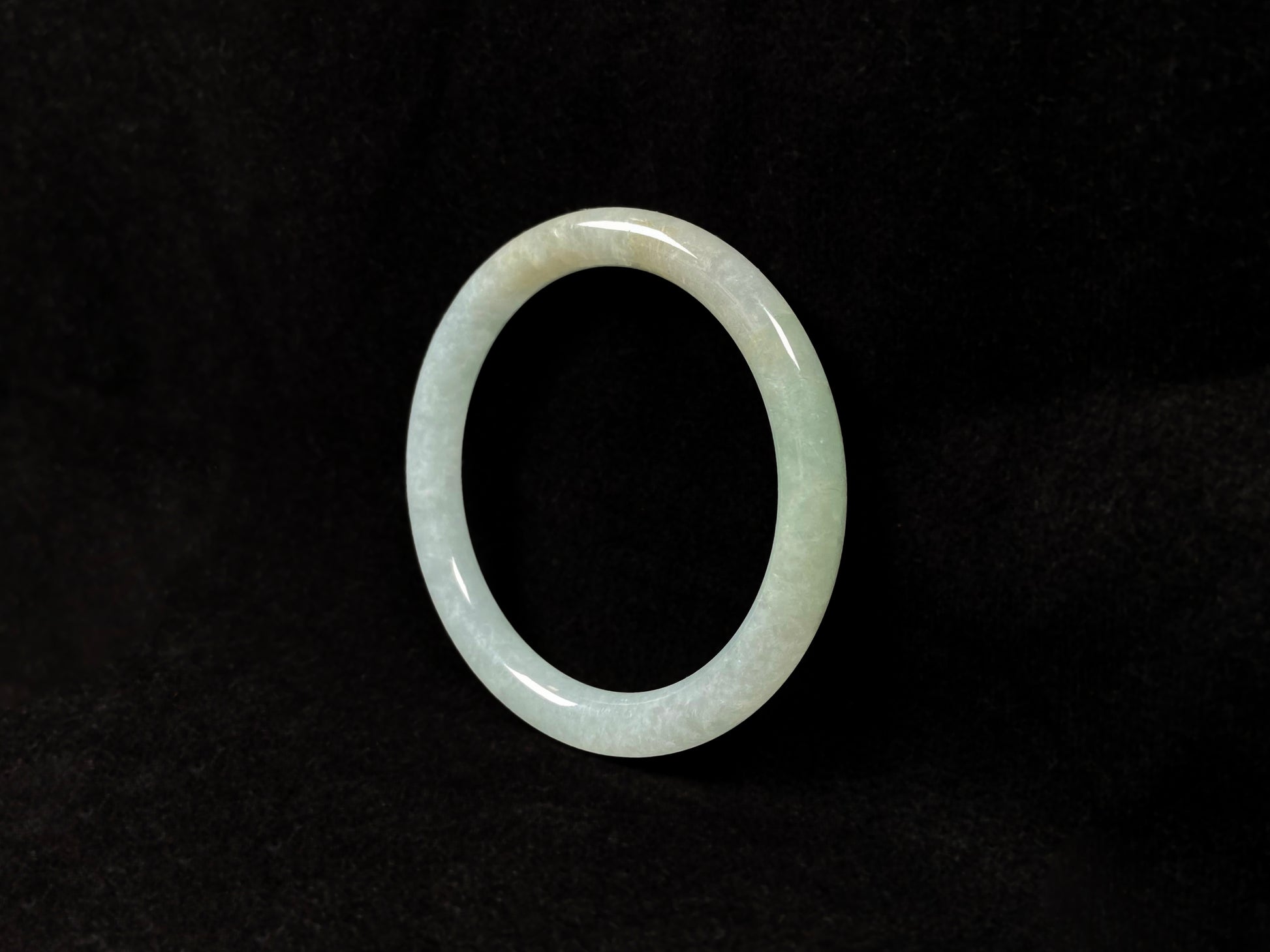 This jadeite bangle has a soft pale cyan base with cream undertones and faint gold streaks.