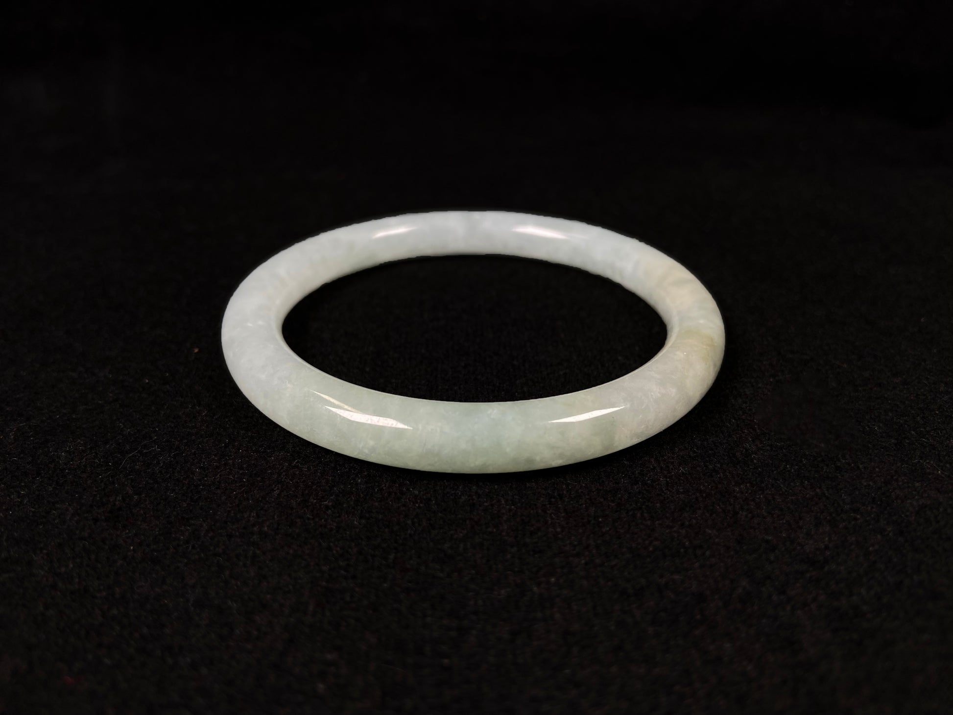 This jadeite bangle has a soft pale cyan base with cream undertones and faint gold streaks.