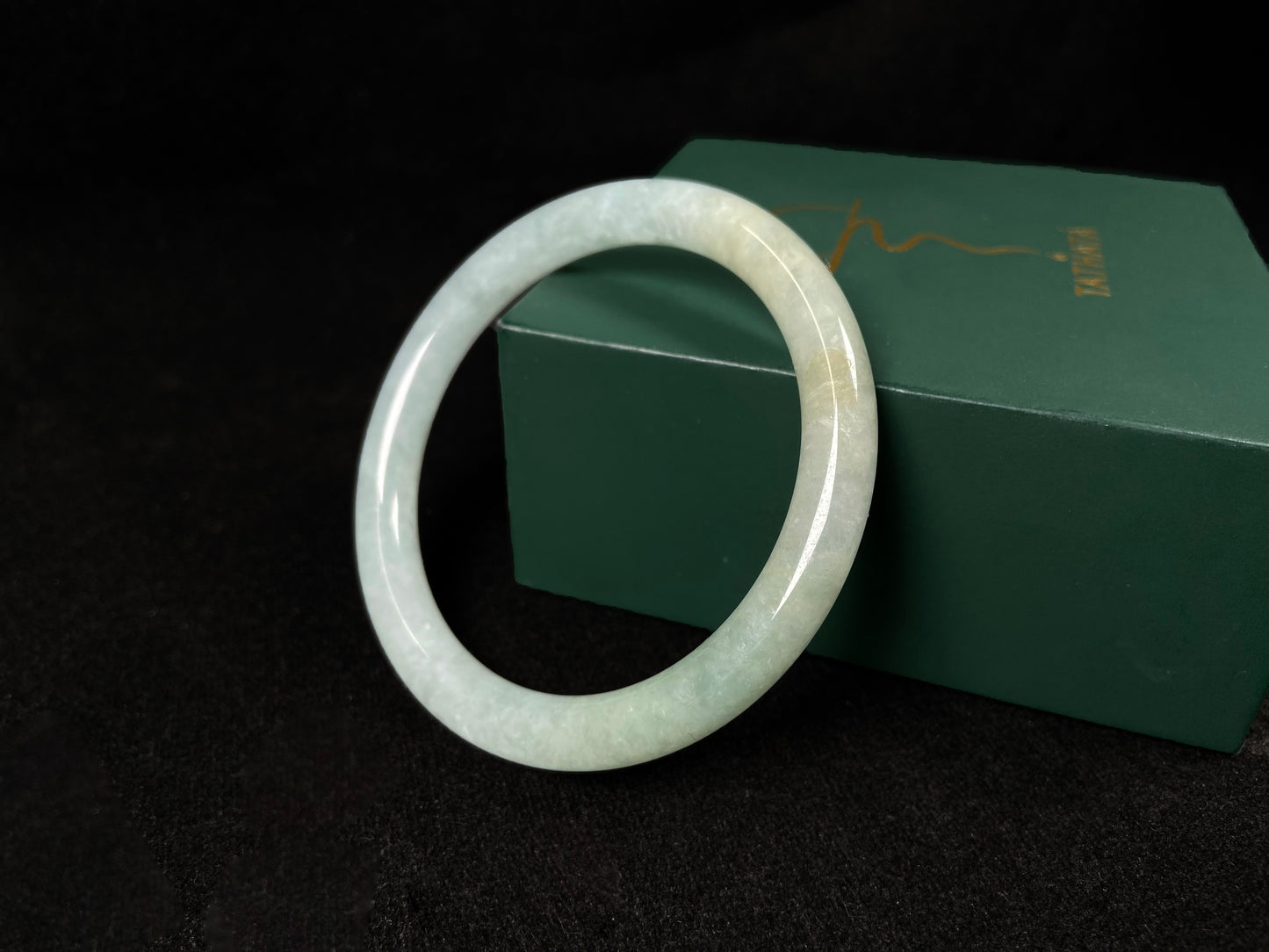 This jadeite bangle has a soft pale cyan base with cream undertones and faint gold streaks.